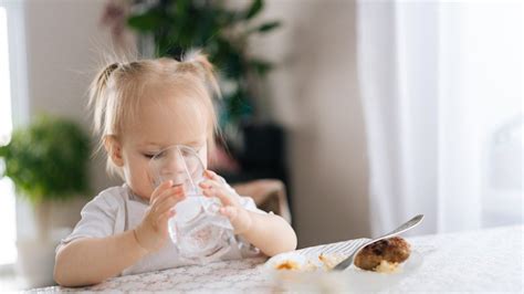 Bambino che impara a bere dal bicchiere