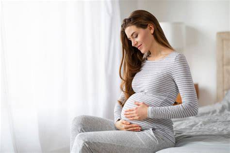 Donna incinta che accarezza il pancione indossando intimo confortevole