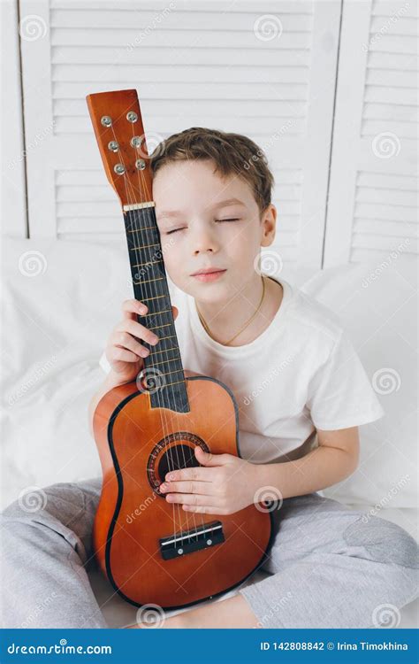 bambino che tiene in mano una piccola chitarra classica con un sorriso entusiasta