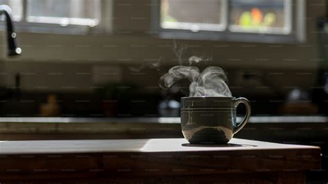 Una tazza di caffè fumante su un tavolo di legno accanto a un ambiente domestico accogliente