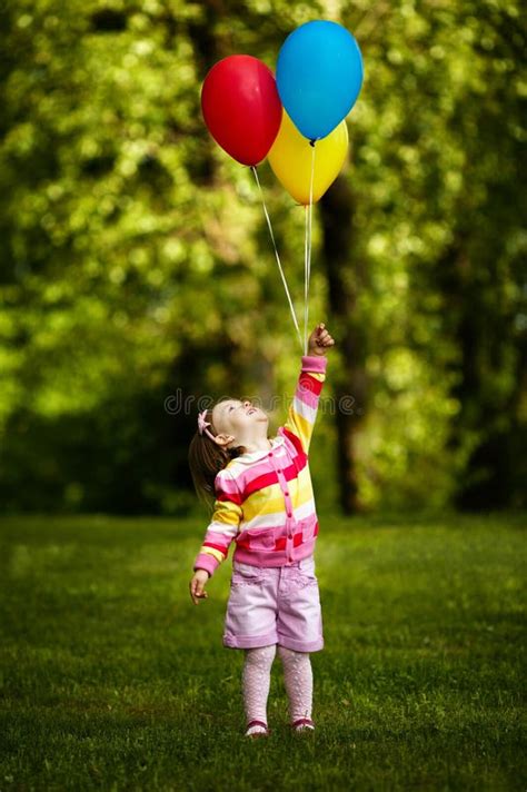 Bambina felice che gioca con palloncini colorati in un parco