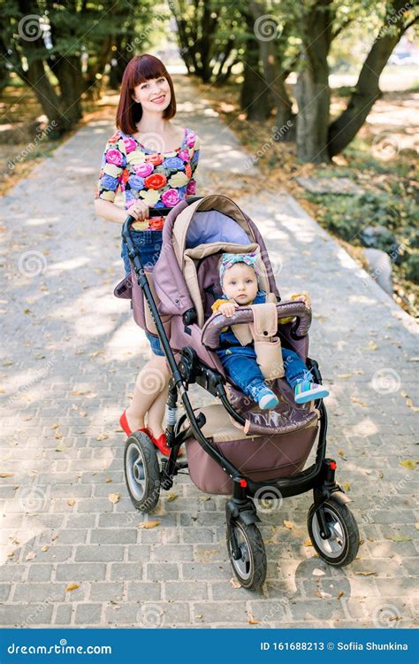 Un bambino sorridente in un passeggino Graco con i genitori felici sullo sfondo
