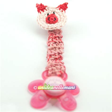 dettaglio ravvicinato di una bambola amigurumi che tiene un ciuccio all'uncinetto