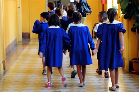 Bambini in grembiule blu all'ingresso della scuola