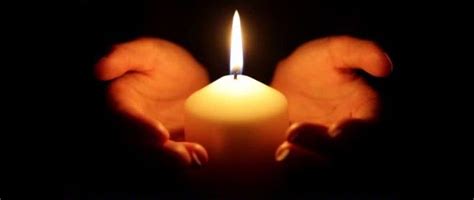 dettaglio di una candela accesa in un contesto di preghiera o ricordo