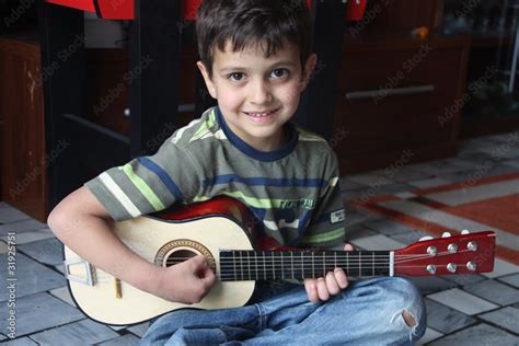 Bambino che suona la chitarra con espressione concentrata