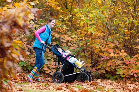genitore che spinge un passeggino in un parco autunnale