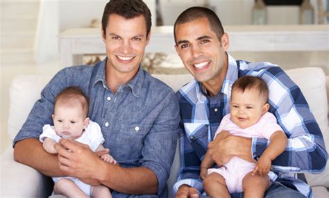 Famiglia moderna con due padri che nutrono il bambino con il biberon in un ambiente sereno