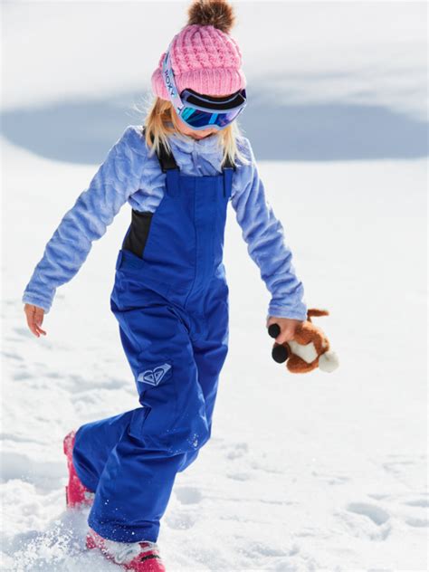 bambina che gioca sulla neve con una salopette tecnica