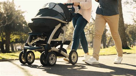 genitori che spingono un passeggino gemellare in un parco