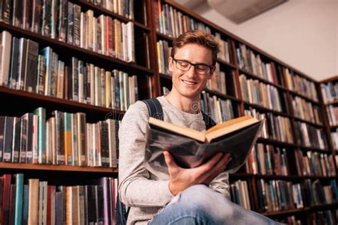 Studente universitario che studia con libri e tablet in una biblioteca luminosa