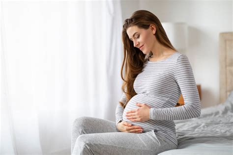 Donna incinta che accarezza il pancione con espressione serena
