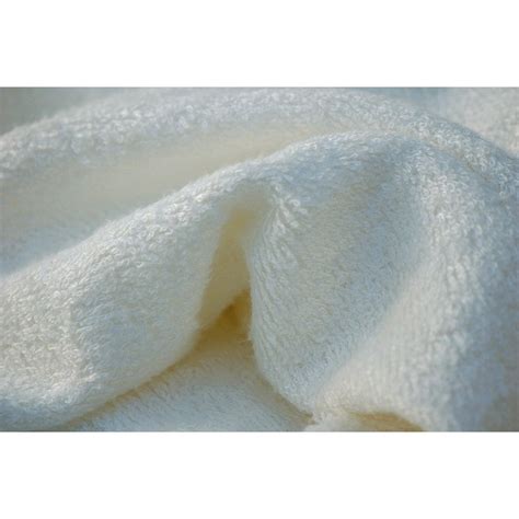 Un accappatoio per neonati in fibra di bambù con orecchie da coniglietto adagiato su una superficie soffice