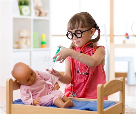 Una bambina che gioca a nutrire la sua bambola in un seggiolone in legno