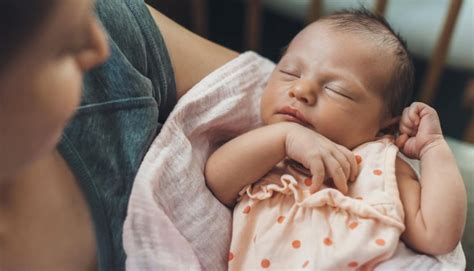 Un neonato che dorme serenamente tra le braccia di un genitore