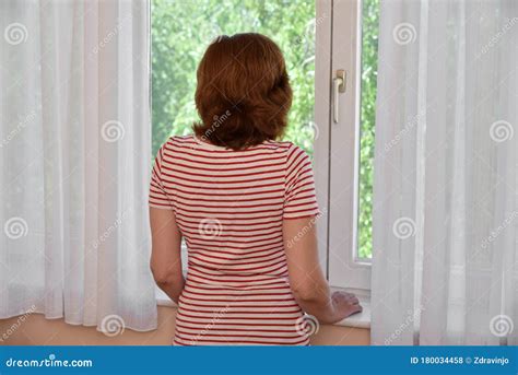 Donna che guarda pensierosa fuori da una finestra