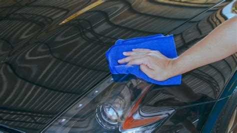 mano con panno in microfibra che lucida una carrozzeria d'auto