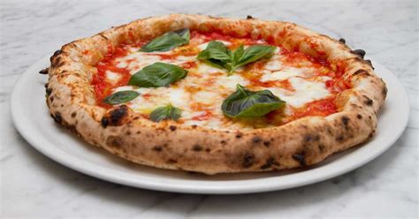 Piatto di pizza margherita fumante e ingredienti freschi