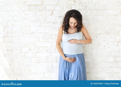 Donna incinta che si tocca la pancia con espressione preoccupata