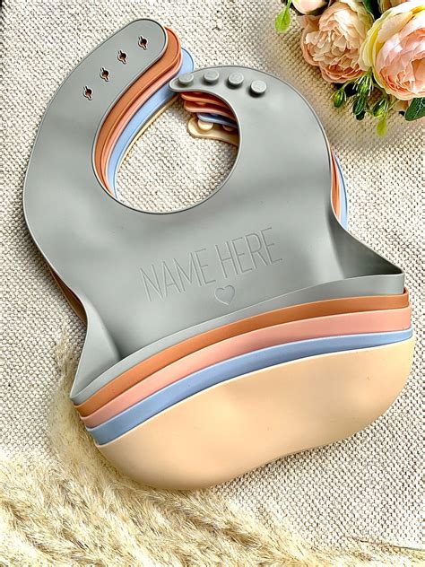 Bavaglino personalizzato in silicone con nome inciso o stampato su un tavolo da cucina