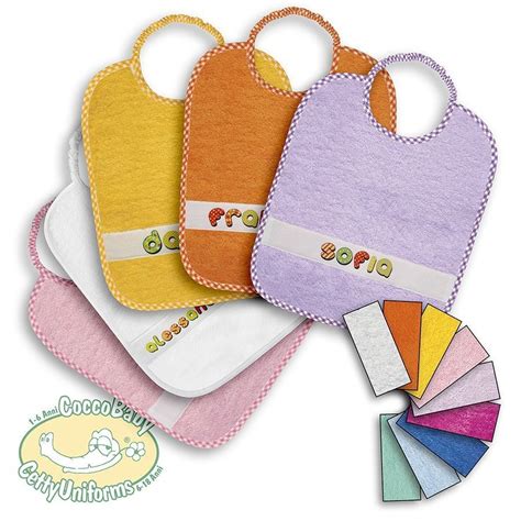 Set di bavaglini colorati impilati in un ambiente scolastico con nomi diversi su ciascuno