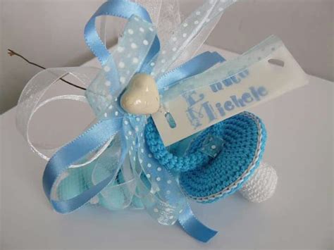 Composizione di bomboniere nascita con piccoli ciucci colorati decorati con nastri di raso