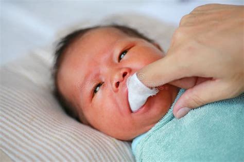 Neonato con garza inumidita che pulisce le gengive