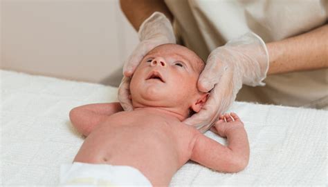 genitore che lava delicatamente la testa di un neonato in una vaschetta