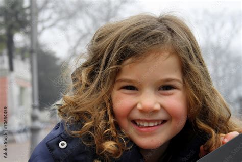 Bambina che ride indossando un piumino leggero in un parco