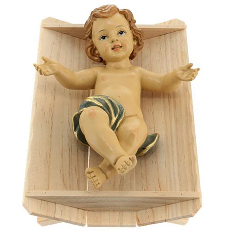 Gesù Bambino nella culla in legno artigianale in un contesto di stalla rustica