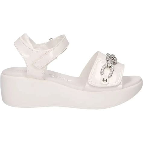 Una selezione assortita di sandali eleganti e casual per bambina esposti su una superficie chiara