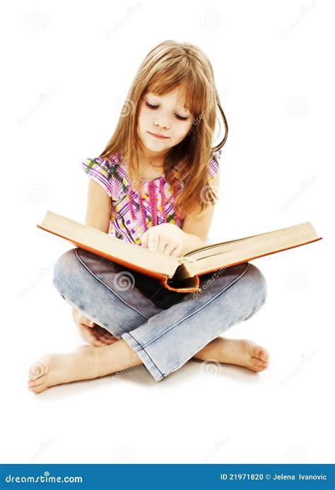 Una bambina che legge un libro colorato seduta sul pavimento di una biblioteca domestica