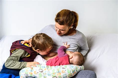 Madre che allatta il neonato mentre il fratello maggiore legge un libro accanto a lei