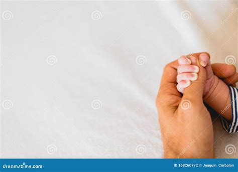 Mani di un neonato che afferra il dito di un adulto