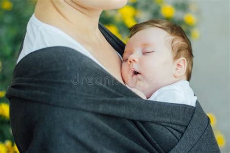 Una madre che porta il proprio bambino in una fascia ergonomica durante una passeggiata in un parco