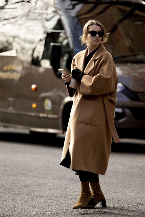 Moda autunnale con stivaletti neri e cappotto cammello