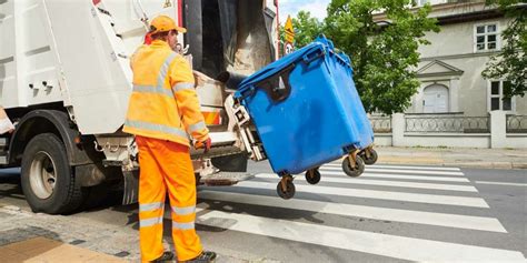 Operatori ecologici che caricano i rifiuti nel mezzo di raccolta