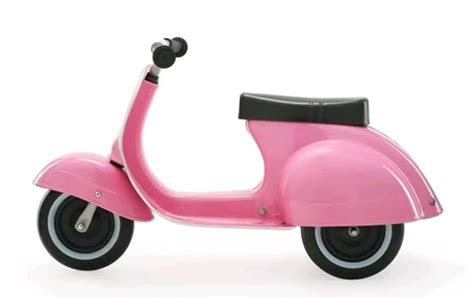 Bambino alla guida della Vespa giocattolo in un parco