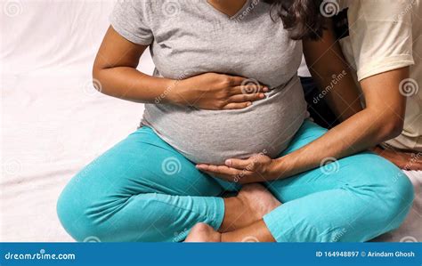 Donna incinta con le mani sulla pancia e il bambino che scalcia