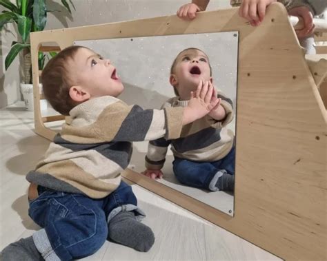 Bambino che osserva la propria immagine in uno specchio montessoriano a terra