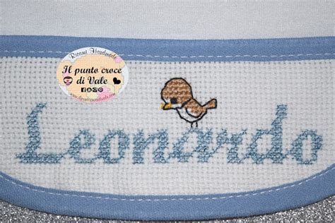 dettaglio macro di un ricamo a punto croce finito su bavaglino con nome ben leggibile e bordure coordinate