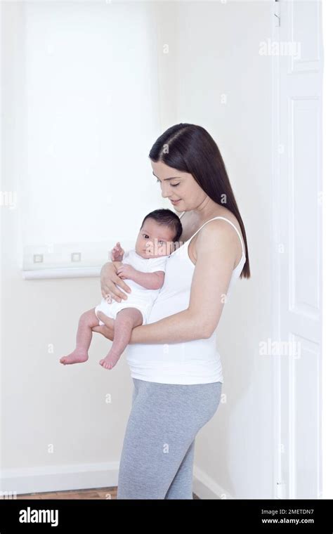 Una madre che culla il proprio bambino in un ambiente domestico d'altri tempi