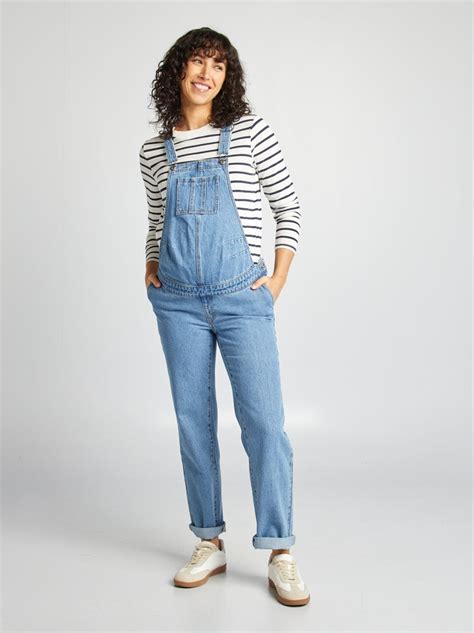 Donna incinta che indossa una salopette premaman in denim in un contesto urbano moderno